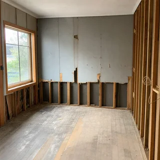 Interior room with old grey fibre cement wall sheeting stripped back to studs
