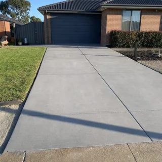 Newly finished plain grey concrete driveway at a suburban home