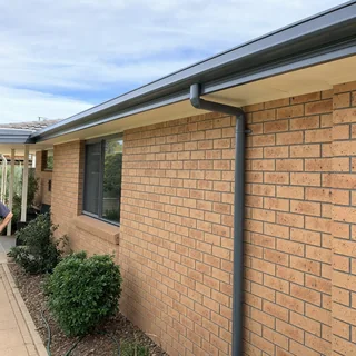 New guttering and downpipe being fitted along the edge of a roof