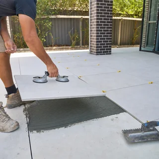 Large outdoor alfresco area tiled in light stone-look pavers beside a pool
