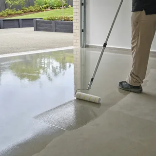 Applicator rolling a fast-cure polyaspartic coating onto a concrete floor